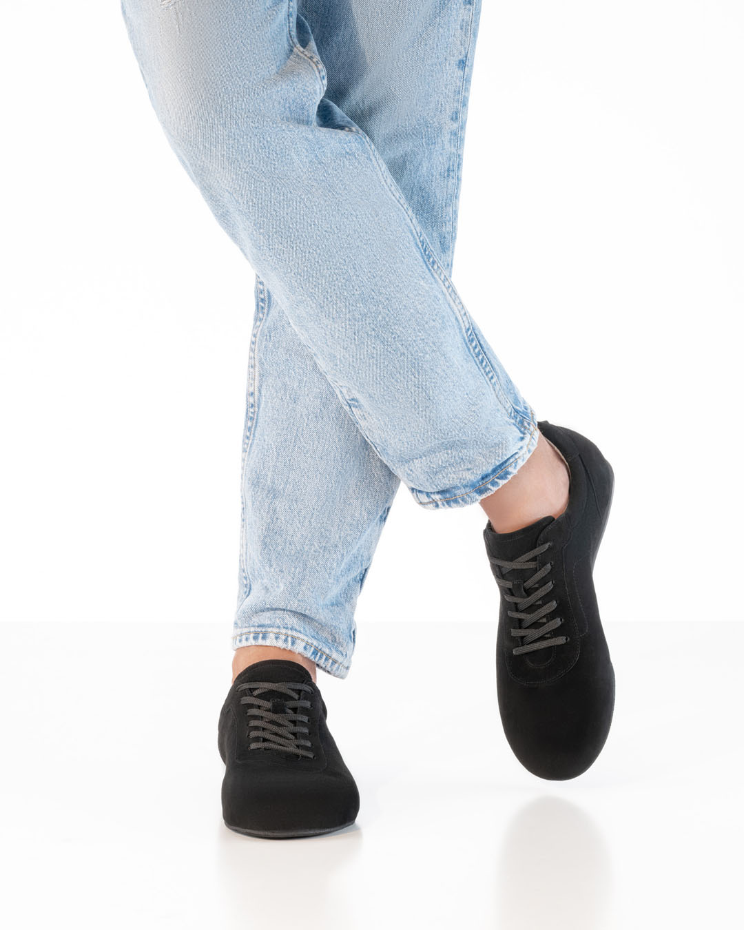 A model in light-coloured jeans and black velour dance trainers by Werner Kern