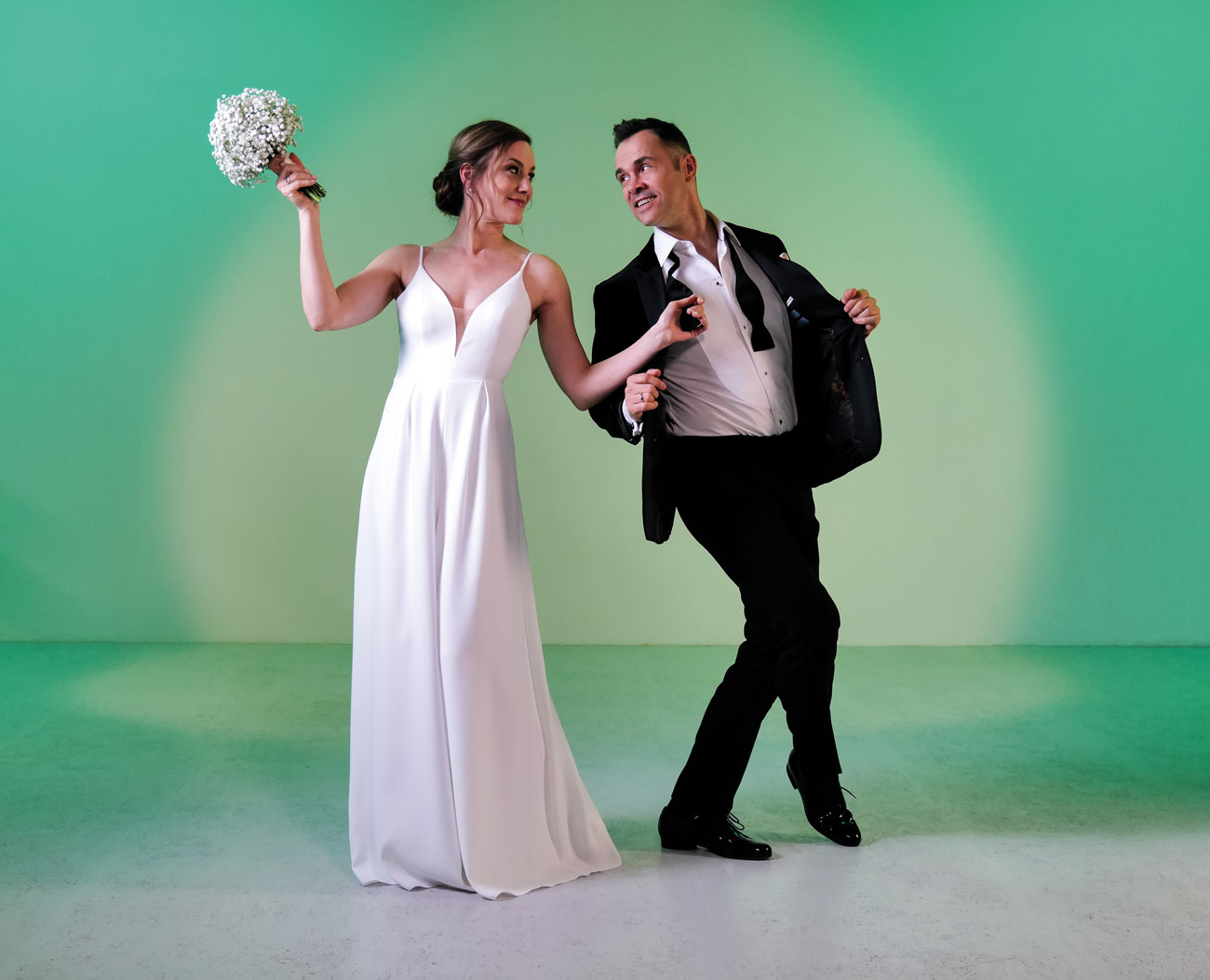 Young bridal couple in bridal dance shoes by Werner Kern Bridal in front of a green studio wall