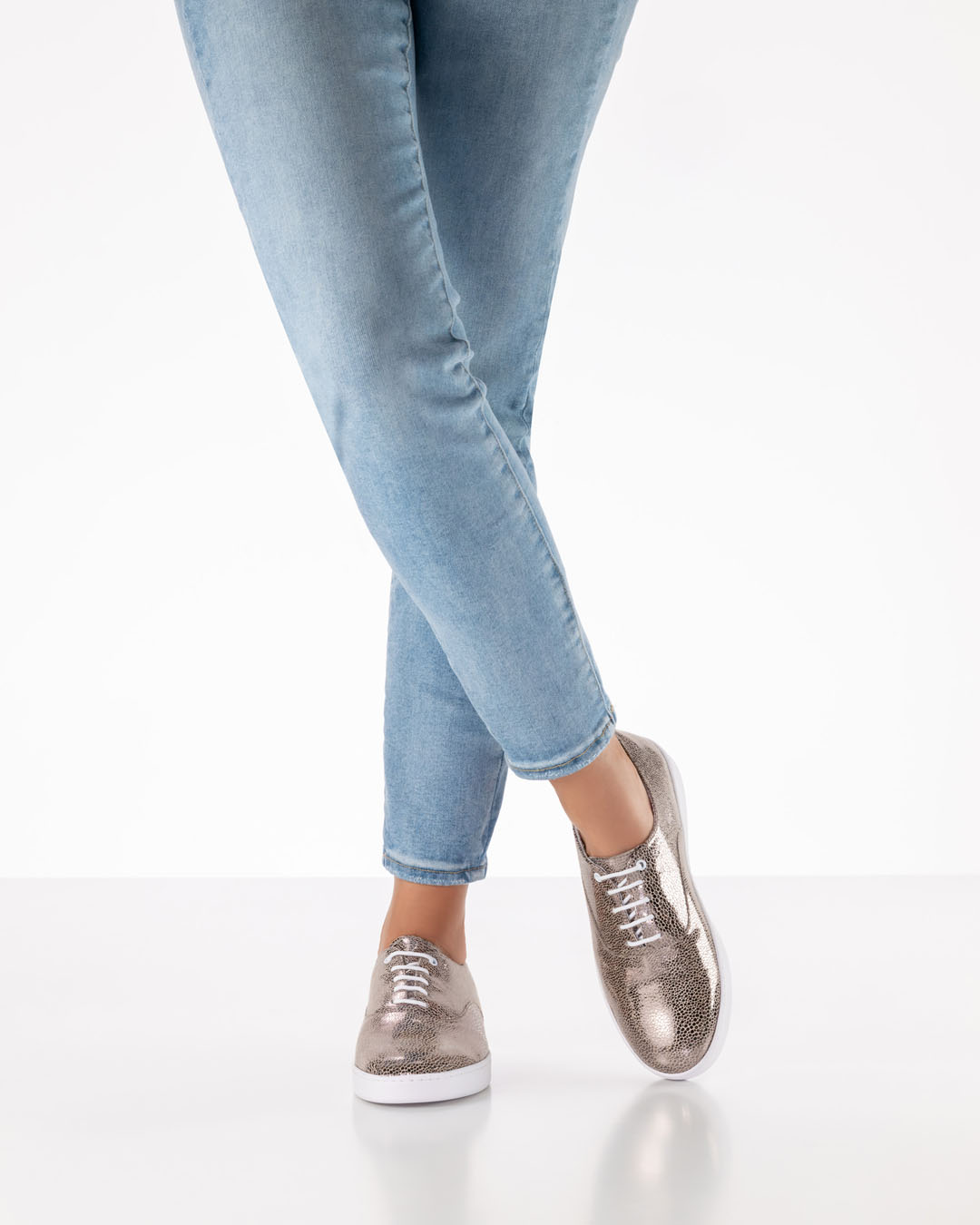 Platinum-coloured, shiny lace-up dance shoes with white soles by Werner Kern, worn with light-coloured jeans