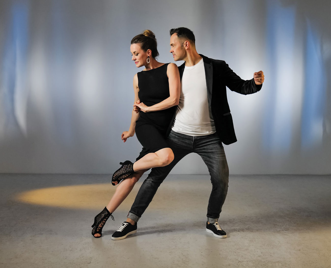 Young dance couple in salsa dance pose with black dance ankle boots and dance sneakers by Anna Kern
