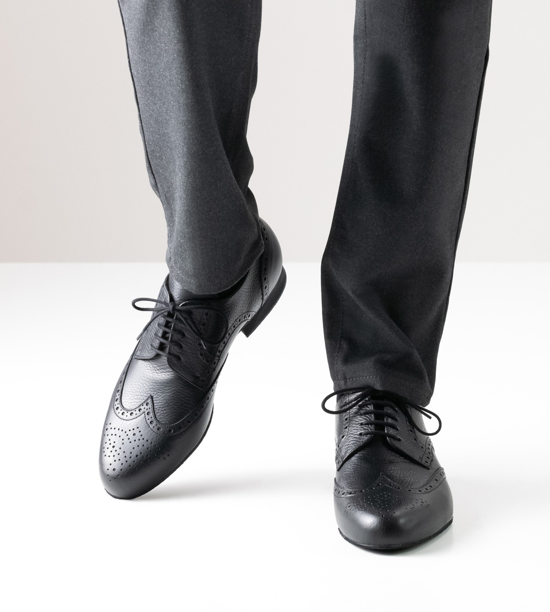 Men's dance shoe in black leather with 2 cm high heel in combination with grey trousers