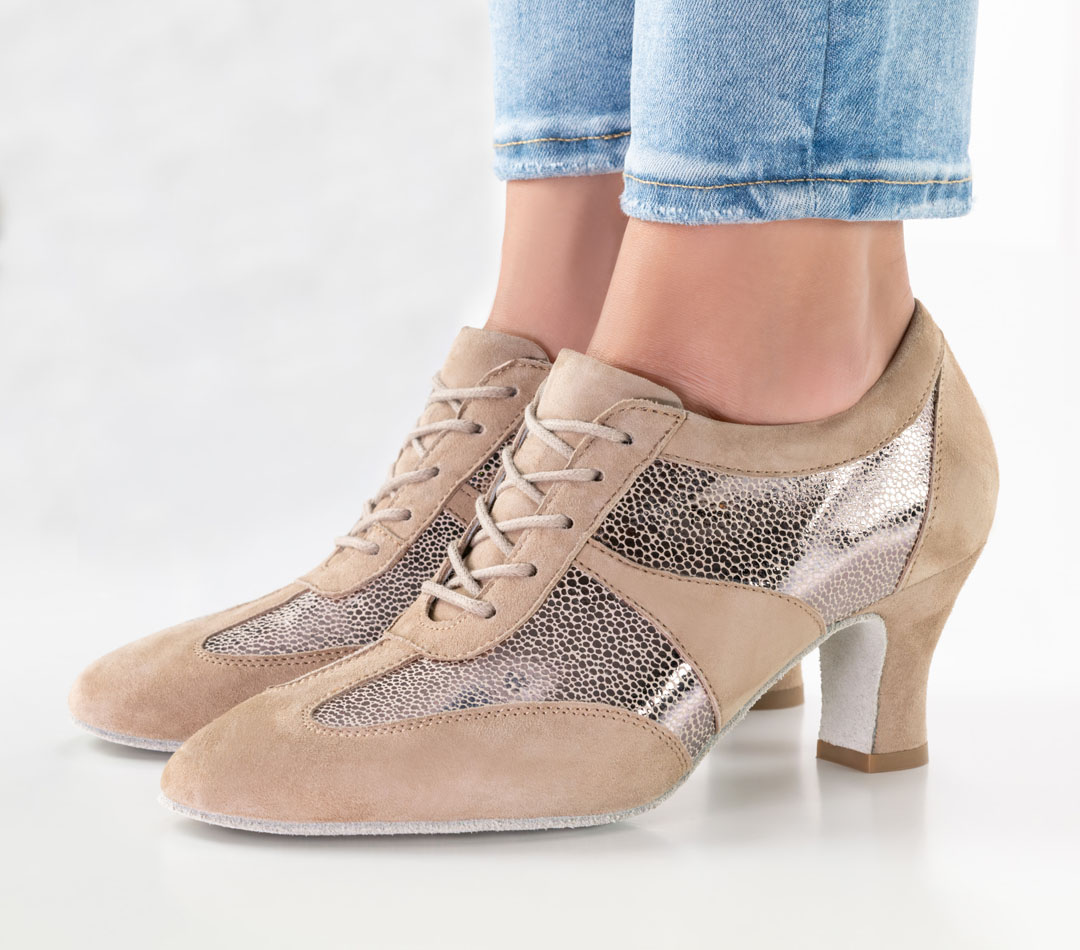 Close-up of a model wearing jeans and beige lace-up trainers with a 6 cm block heel