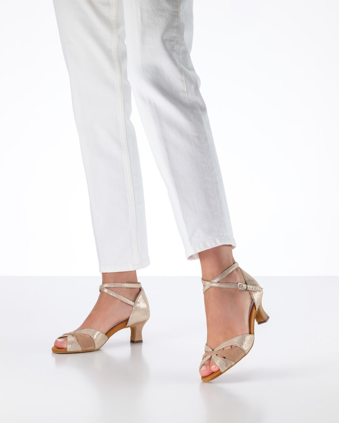 The model is wearing white jeans and a pair of beige ‘Eunice’ dance sandals by Anna Kern