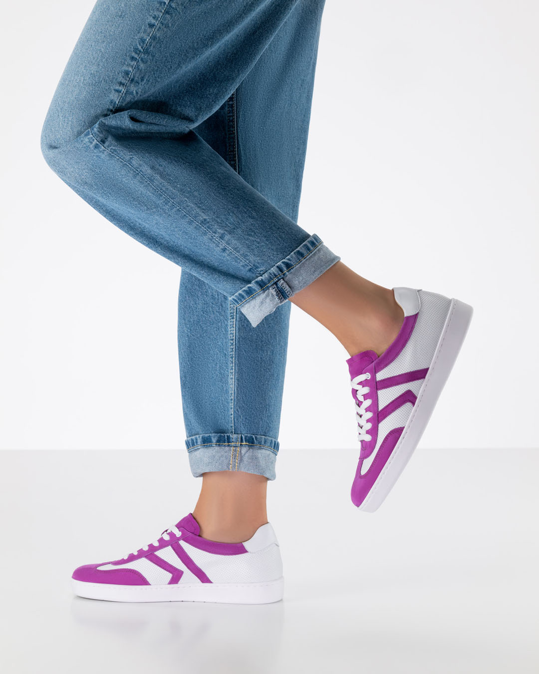 A look featuring loose-fitting jeans and white leather trainers with pink inserts
