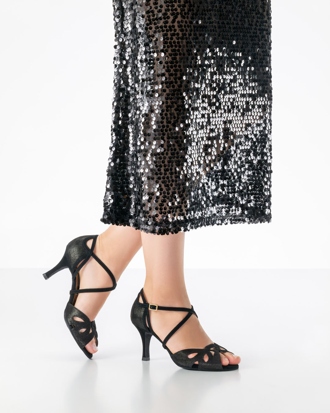 Elora – an open-toed, shimmering black dance shoe with a 7 cm heel by Nueva Epoca, worn with a long black sequinned dress